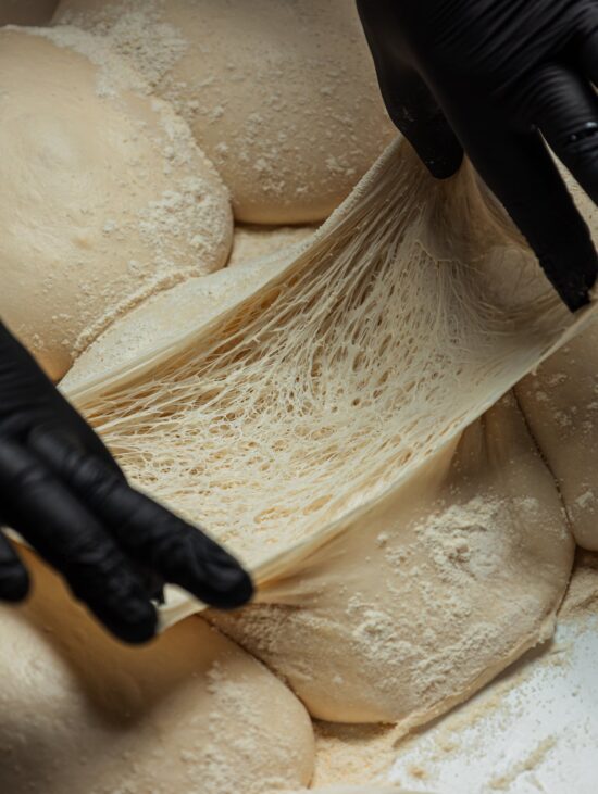 A pizzaiolo stretching dough by hand