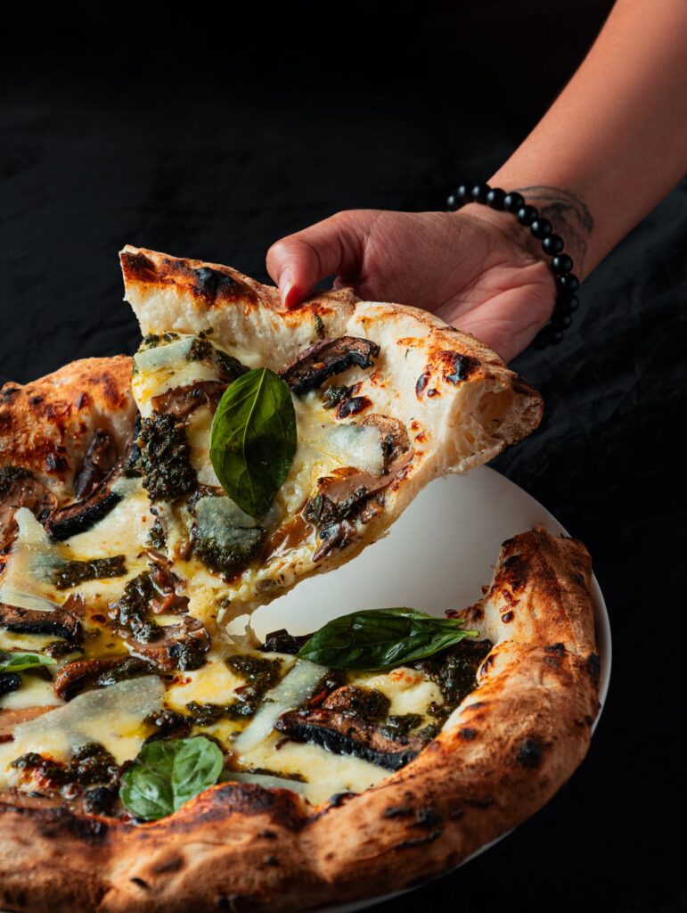 A hand lifting a slice from a white truffle pizza