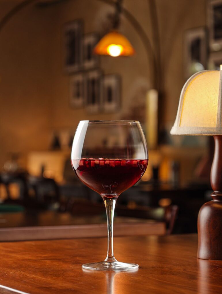 A glass of red wine by a table lamp
