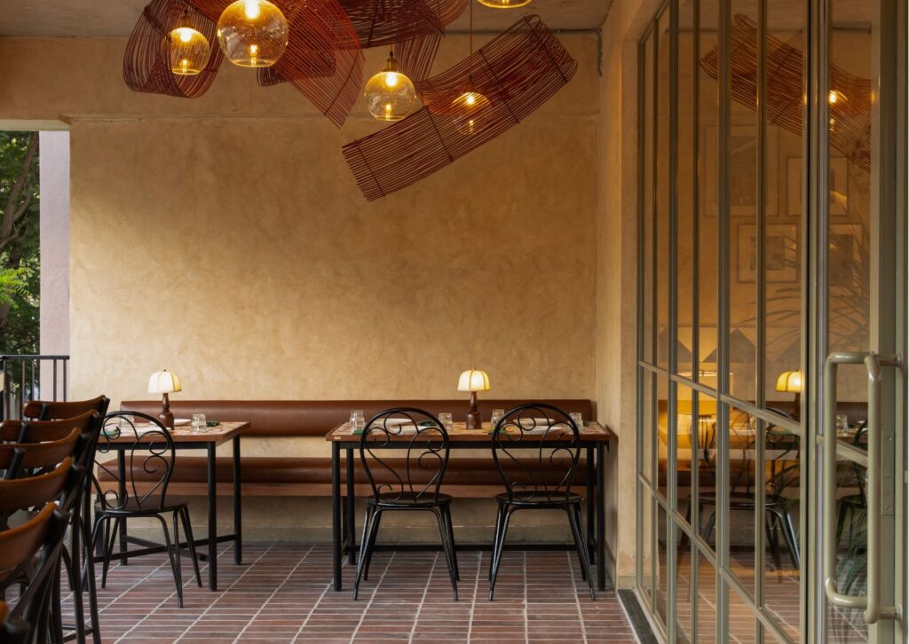Banquette tables on the covered terrace under woven pendant lamps